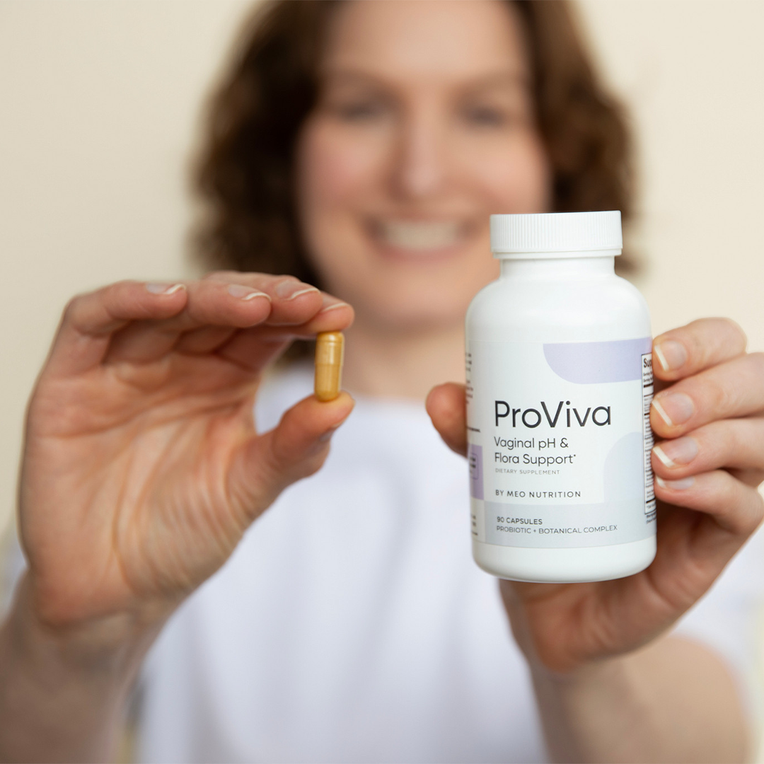 Person holding a ProViva supplement bottle and a capsule in front of a blurred background