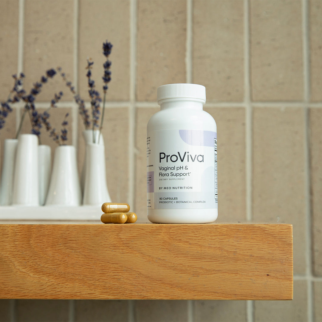 ProViva supplement bottle on a wooden surface with decorative vases in the background.